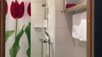A shower with a glass door, a towel rack, and a shelf with toiletries.