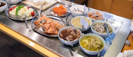 Un bufé con una variedad de platos, incluyendo mariscos, ensaladas y salsas.