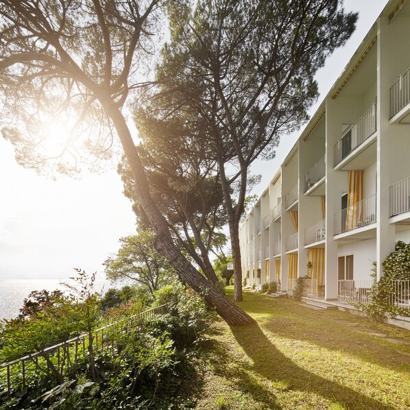 A building with balconies and a grassy area in front. - Hotel Riviera & Maximilians (Trieste)
