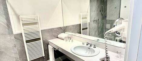 A modern bathroom with two sinks, a large mirror, and a glass shower enclosure.