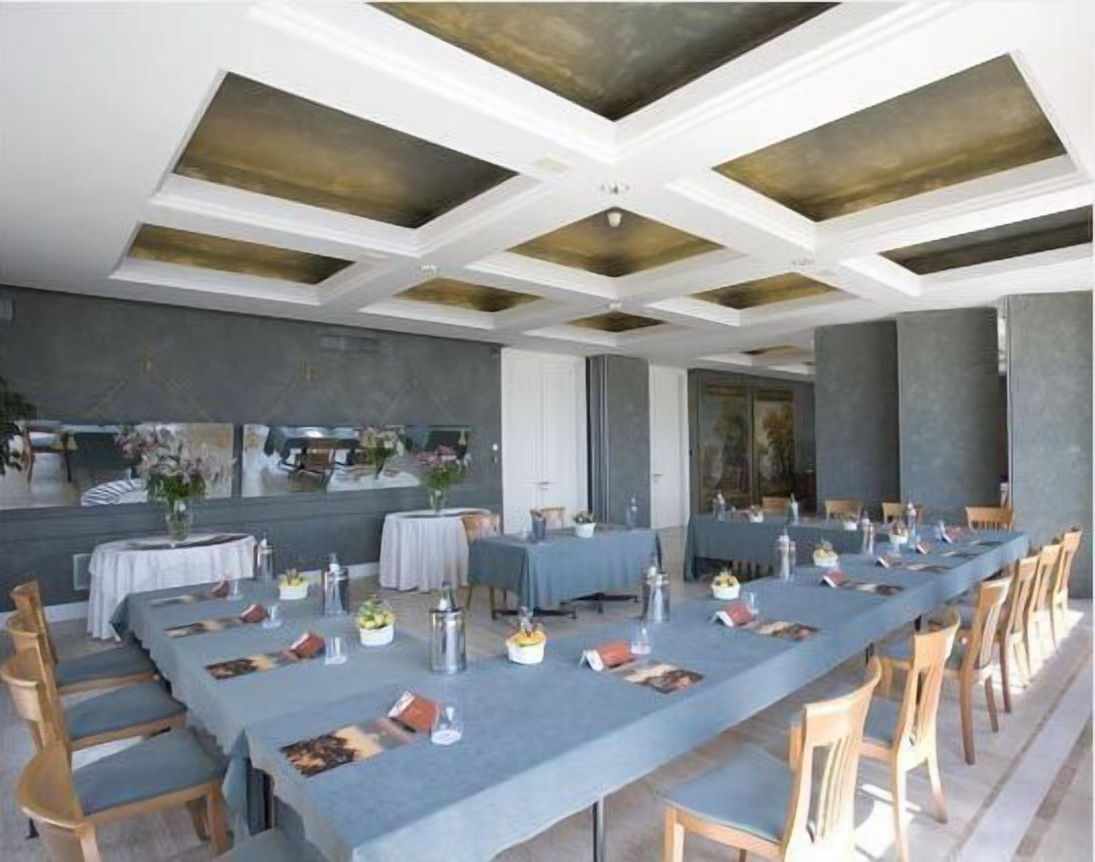 A long dining table set with chairs, a ceiling with geometric patterns, and a neutral color scheme.