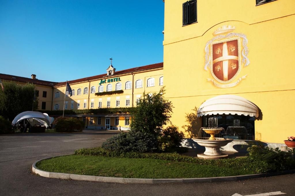 Un hotel con uno stemma ben visibile, una fontana e un giardino curato.