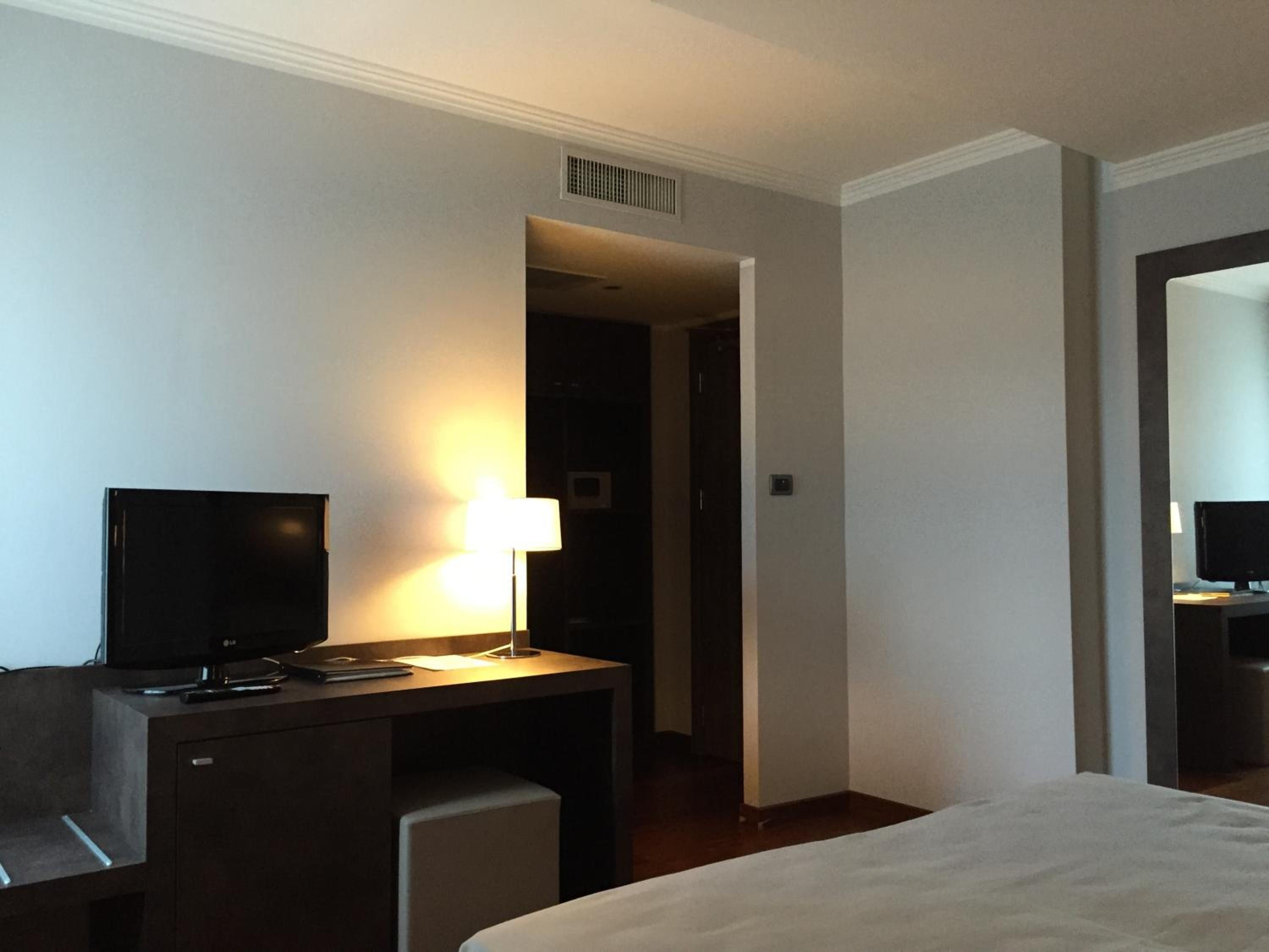 Une chambre d’hôtel avec un lit, un bureau doté d’une lampe, une télévision et une chaise.