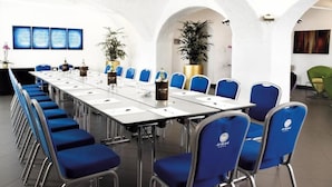 A conference room with a long table, blue chairs, and potted plants.