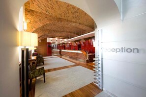 A reception area with a curved brick ceiling, a reception desk, and a seating area with chairs and a table.