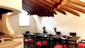 Un comedor con techo alto, vigas de madera y chimenea de ladrillo.