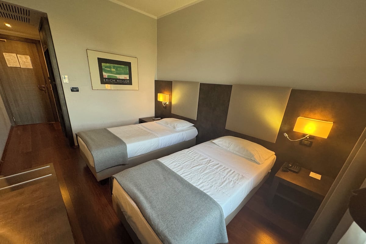 Habitación de hotel con dos camas, un cuadro en la pared y lámparas de noche.