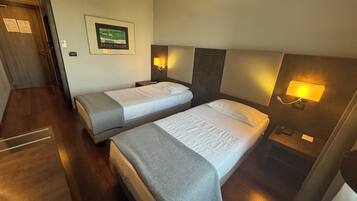 A hotel room with two beds, a framed picture on the wall, and bedside lamps.