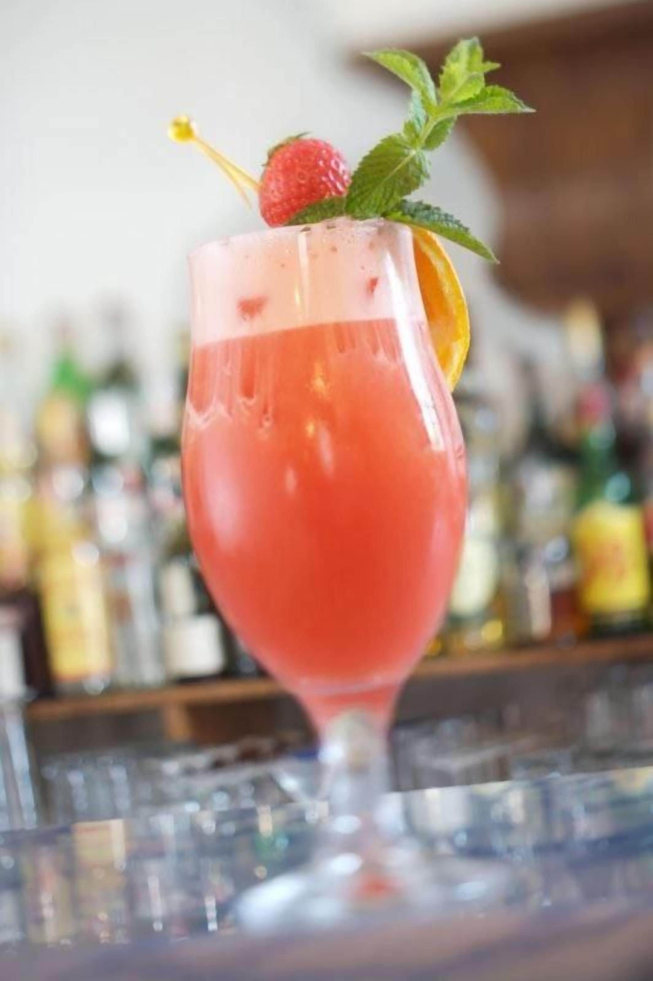 A cocktail glass with a strawberry garnish on a bar counter.