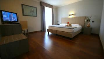 Ein Hotelzimmer mit einem Bett, einem Fernseher, einem Sessel und einem Nachttisch.