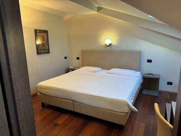 Un dormitorio con una cama grande, una mesita de noche, una lámpara de pared y un cartel en la pared.