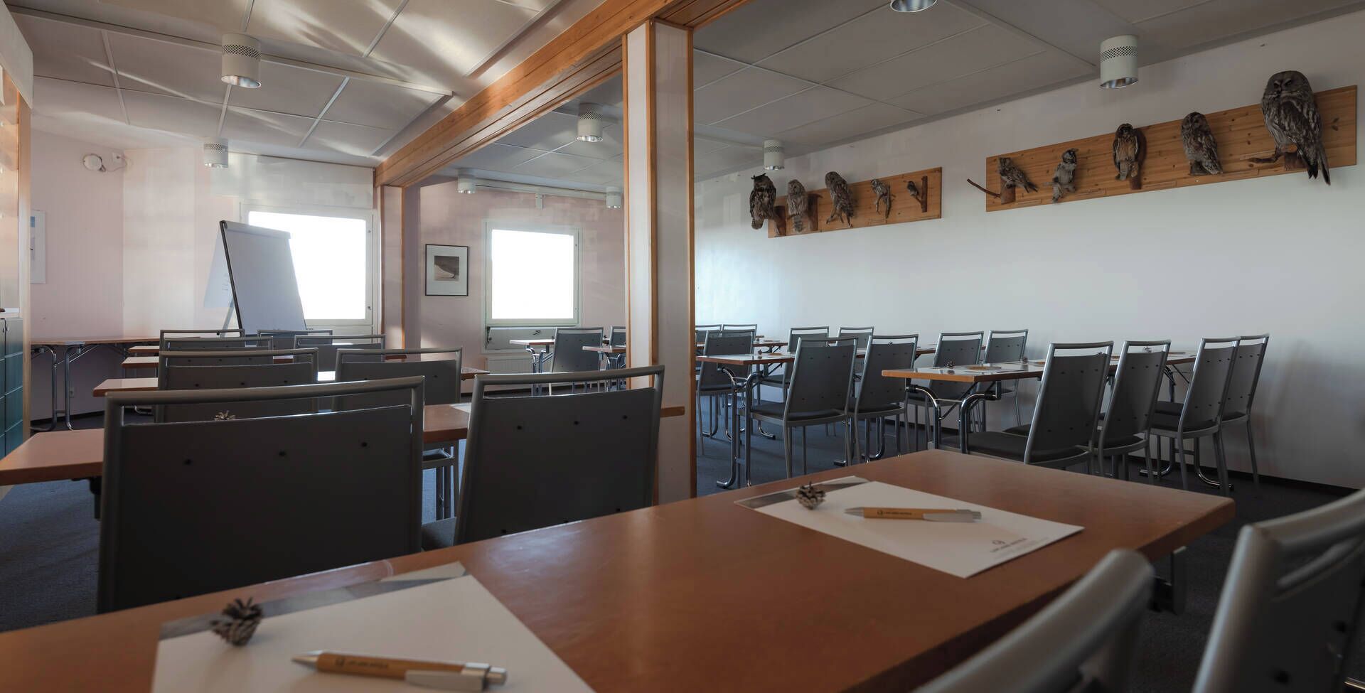 Una sala conferenze con diversi tavoli e sedie, decorazioni in legno alle pareti e un'ampia finestra.