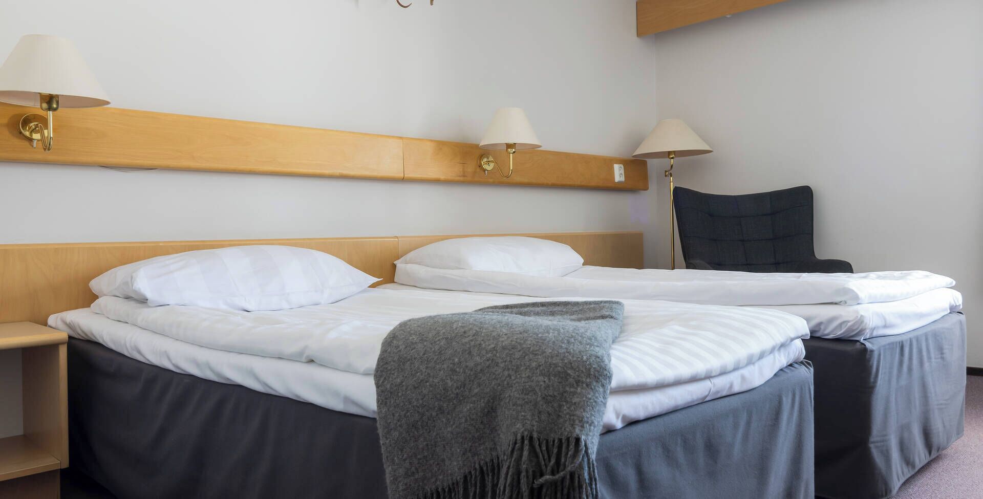 Habitación de hotel con una cama doble, dos mesitas de noche y dos lámparas de pared.