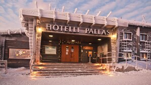 A wooden building with a sign reading "HOTELLI PALLAS" and a wooden staircase leading to the entrance. - Lapland Hotels Pallas (Muonio)