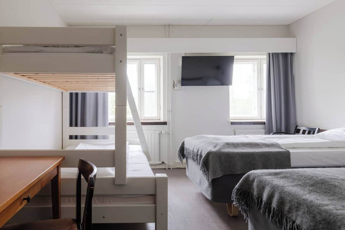Ein Hotelzimmer mit Etagenbett, Schreibtisch und Fernseher.