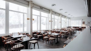 A spacious restaurant with high ceilings, large windows, and a long counter. - Lapland Hotels Kilpis (Enontekio)