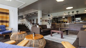 A modern lobby with a reception desk, seating area, and staircase. - Lapland Hotels Kilpis (Enontekio)