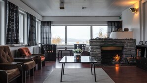 A modern living room with a fireplace, seating, and a view of the outdoors. - Lapland Hotels Kilpis (Enontekio)