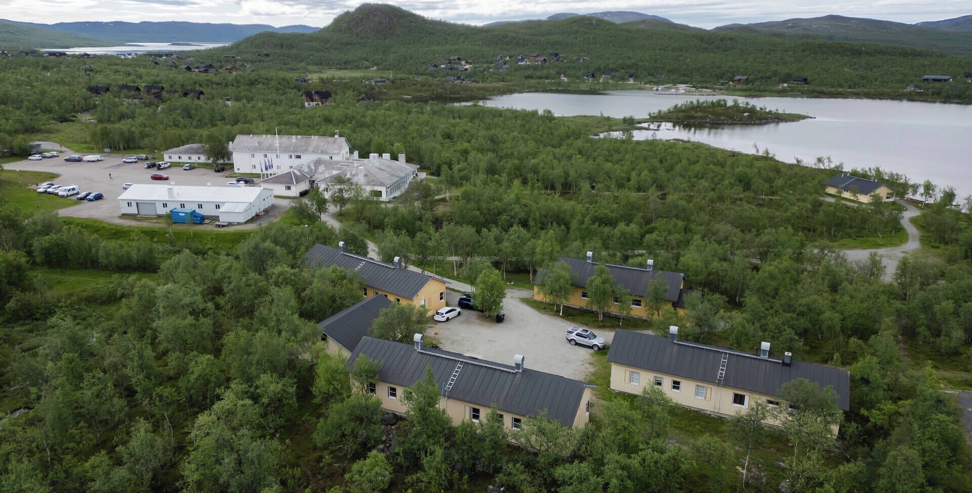 An aerial view of a residential area with houses, a parking lot, and a lake.