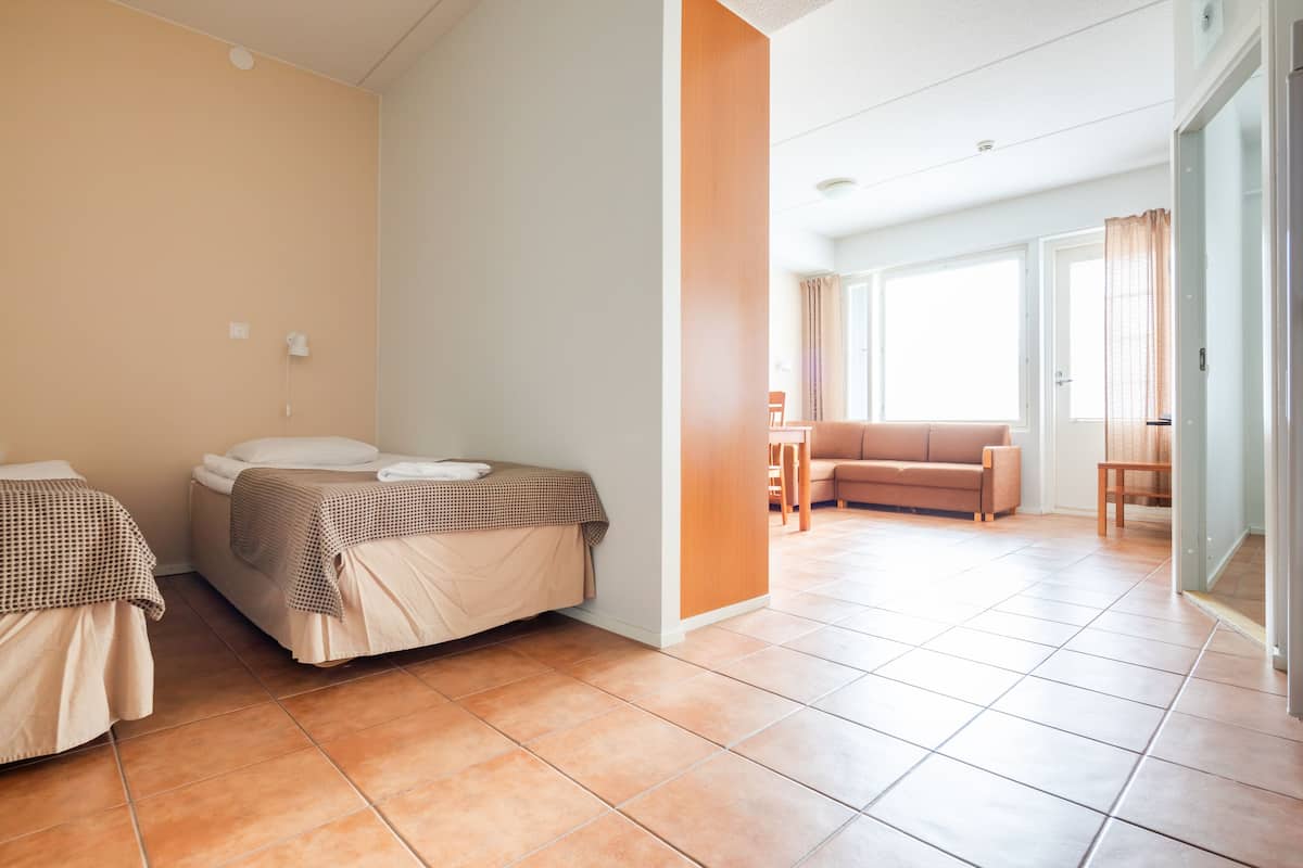 Habitación de hotel con dos camas, un sofá y un comedor.