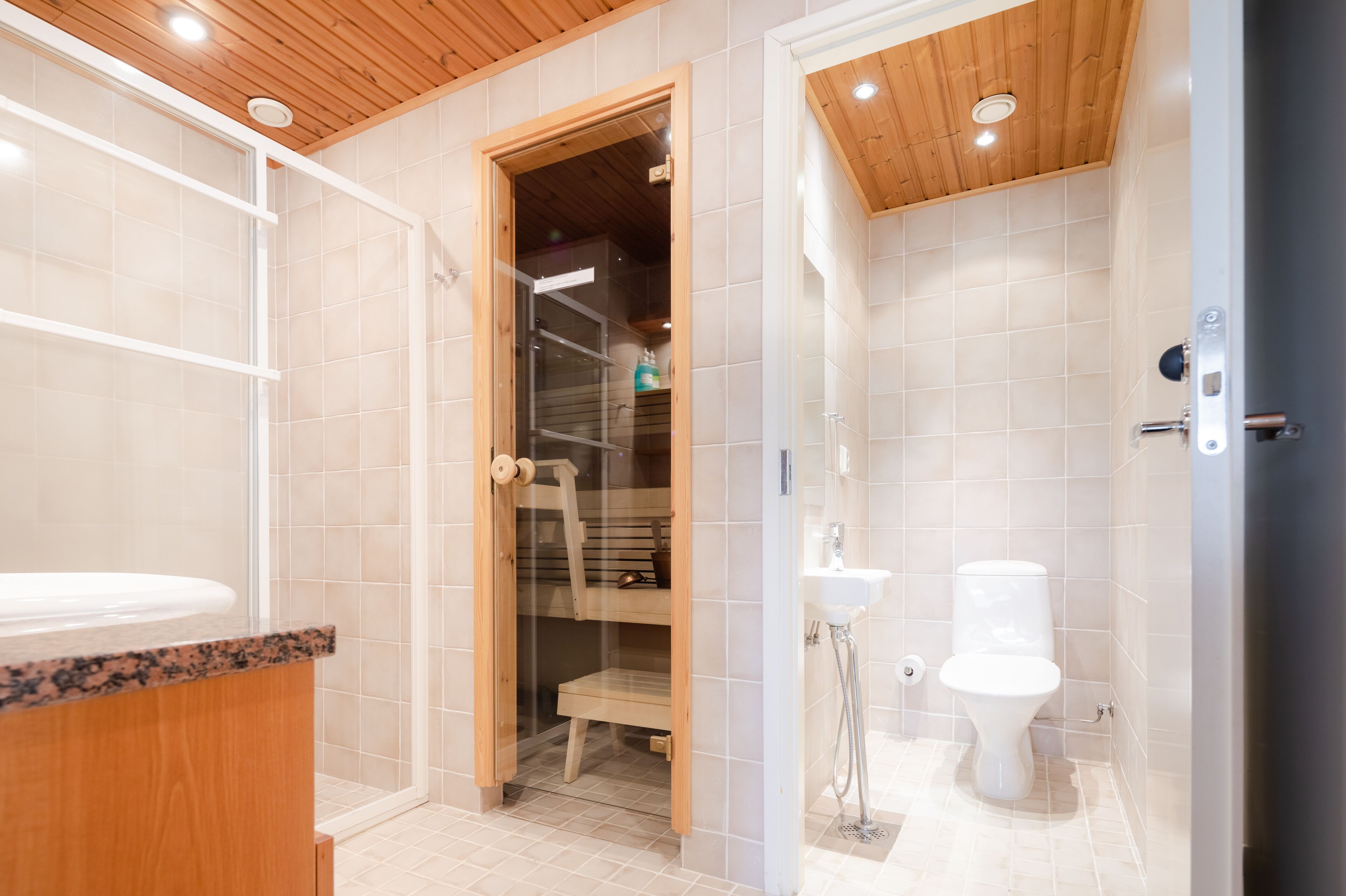 Ein modernes Badezimmer mit Waschtisch aus Holz, einer Duschkabine aus Glas und einer separaten Toilette.