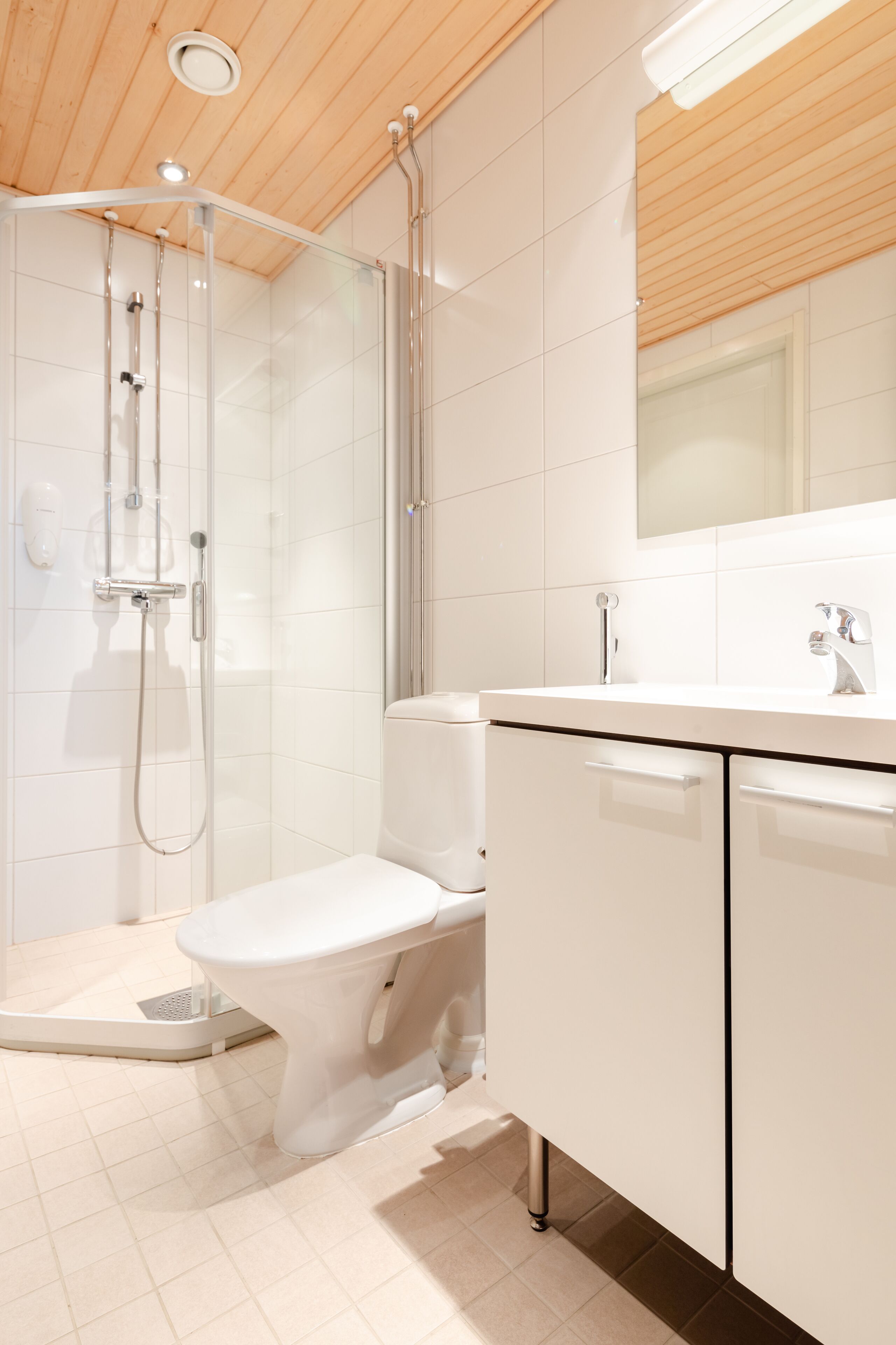 Un baño moderno con ducha, inodoro y muebles blancos.