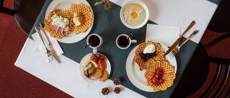 Una mesa con platos de gofres, tazones de sopa y tazas de café.