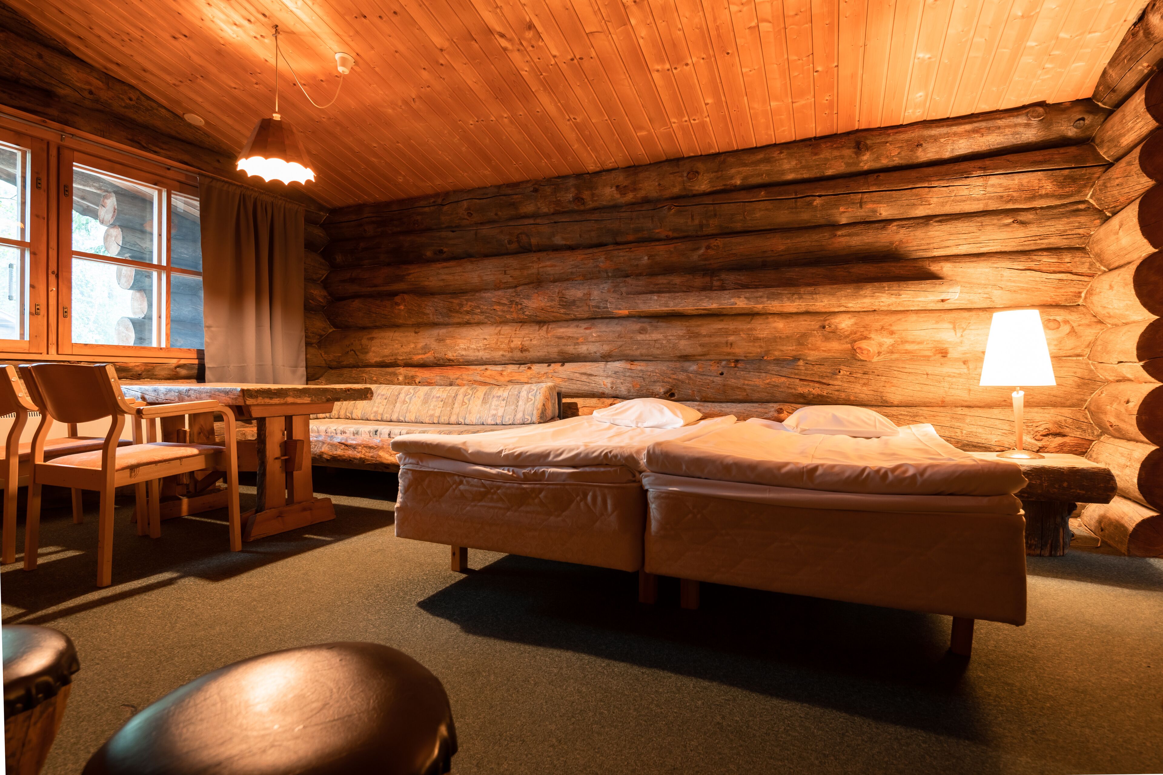 Una habitación tipo cabaña de madera con una cama, un escritorio y una silla.