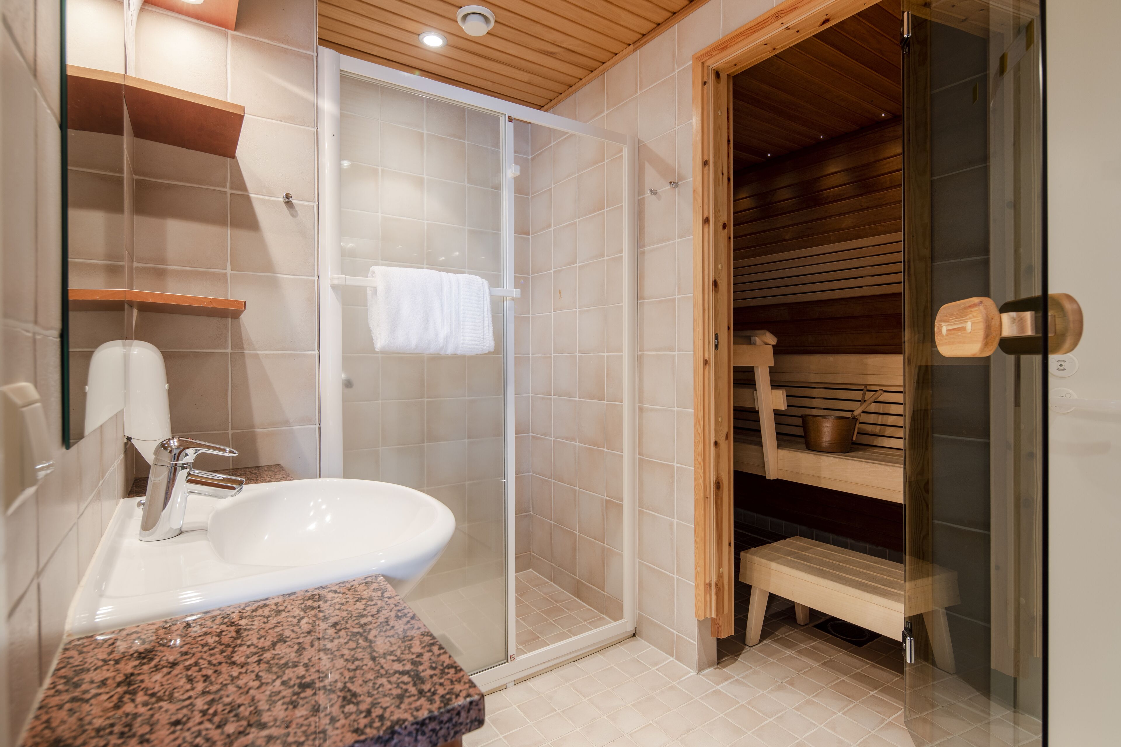 A modern bathroom with a glass-enclosed shower, a white sink, and wooden shelves.