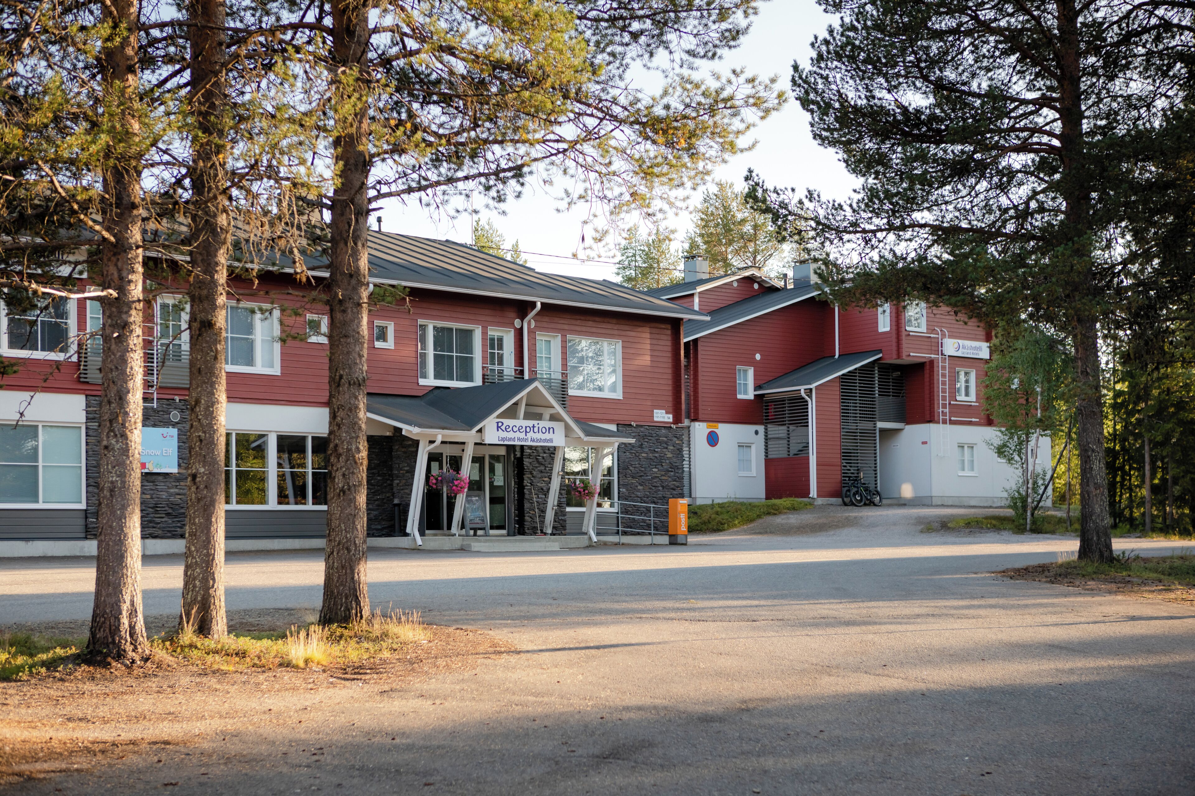 A red building with a reception area, a covered entrance, and a parking lot.