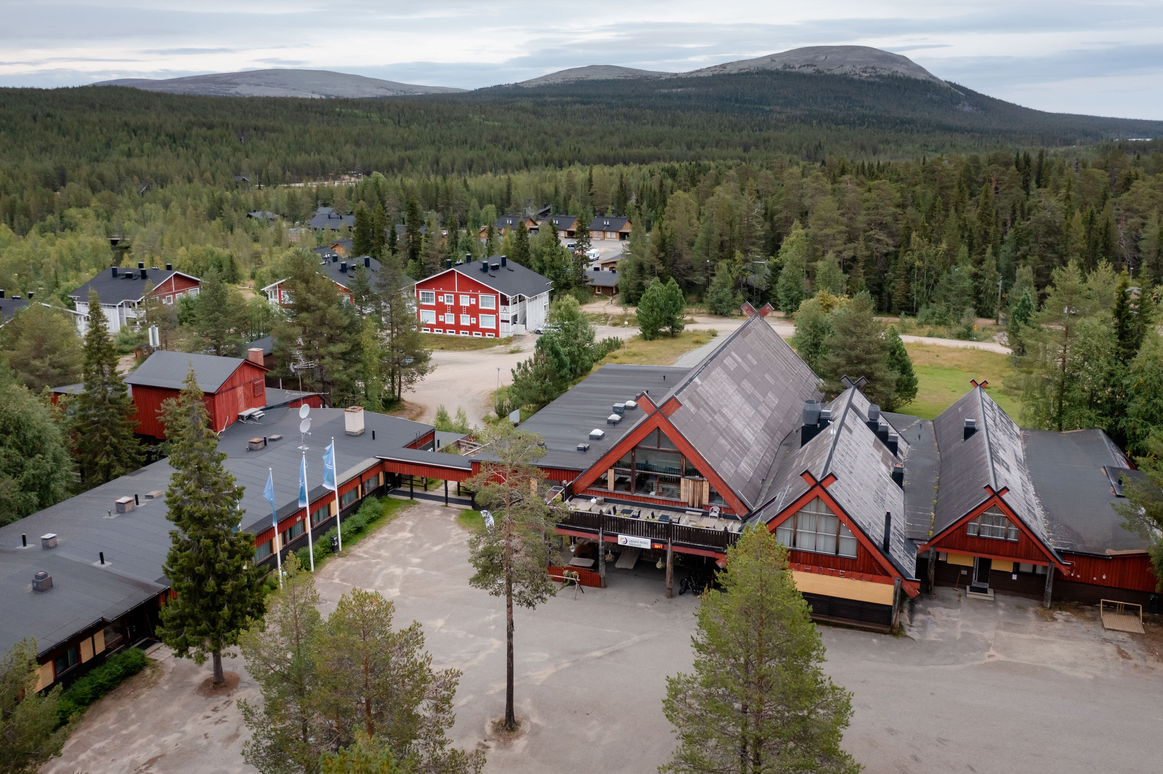 En anläggning med flera byggnader, en parkeringsplats och en skog som utgör bakgrunden.