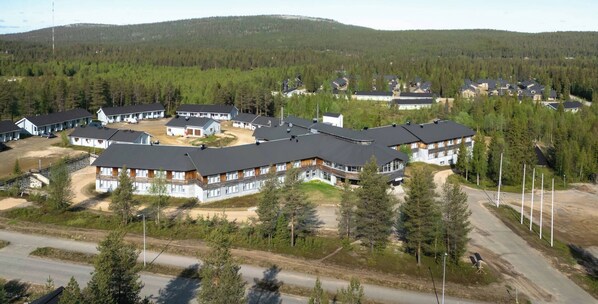 A large resort with multiple buildings, a central courtyard, and a forested backdrop.