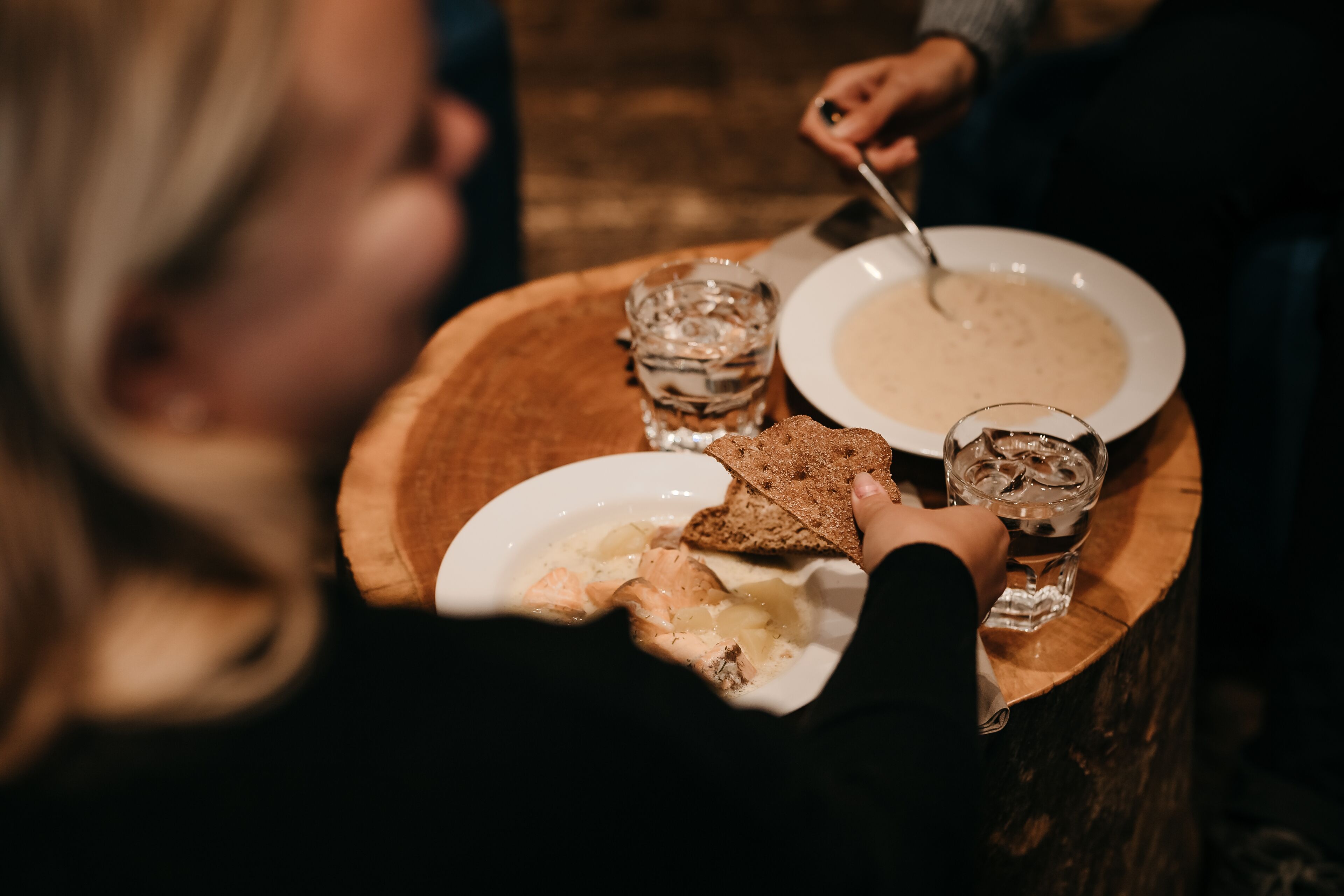 A dining table with a bowl of soup, a glass of water, and a plate of bread.