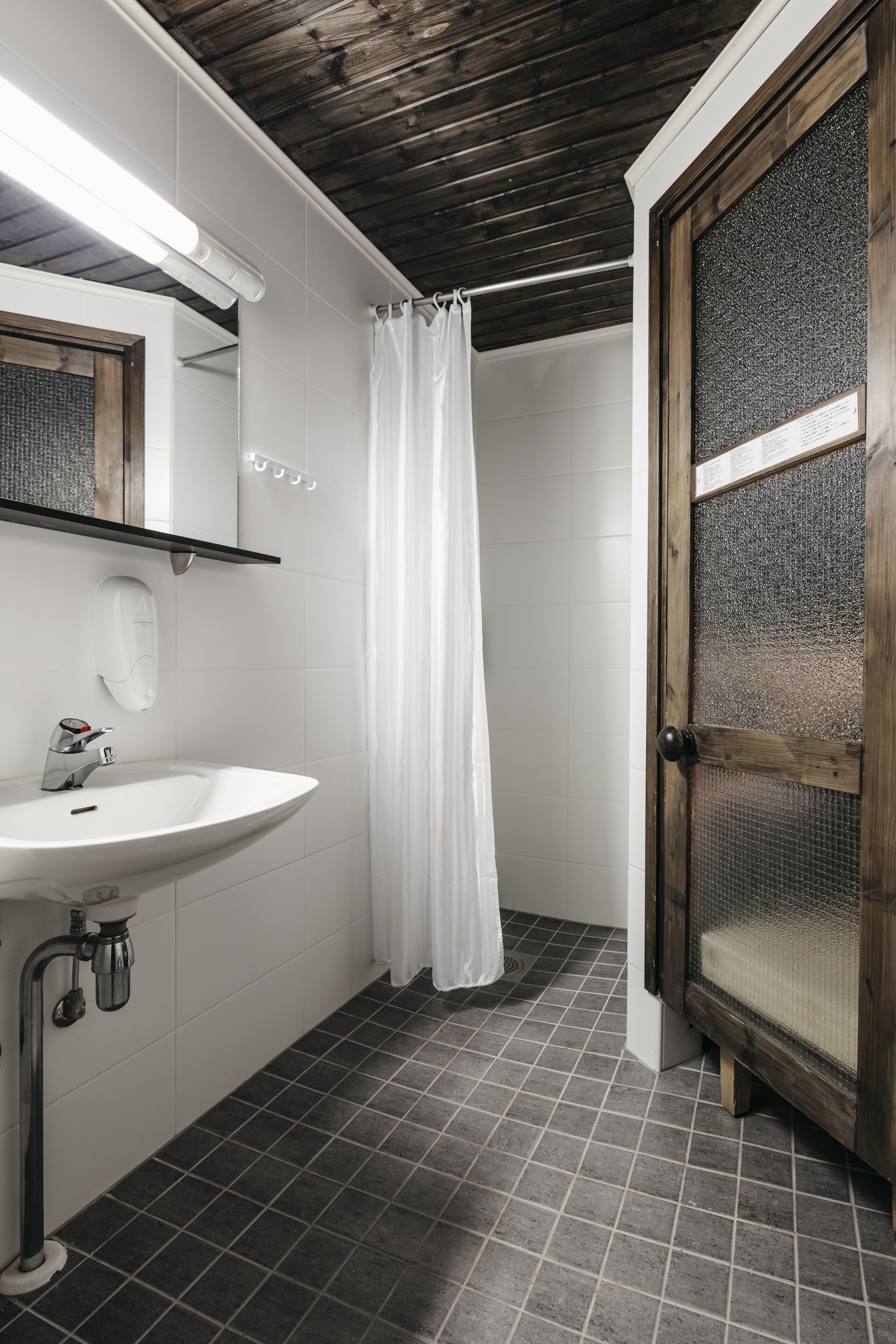A bathroom with a white sink, a wooden door, and a shower curtain.