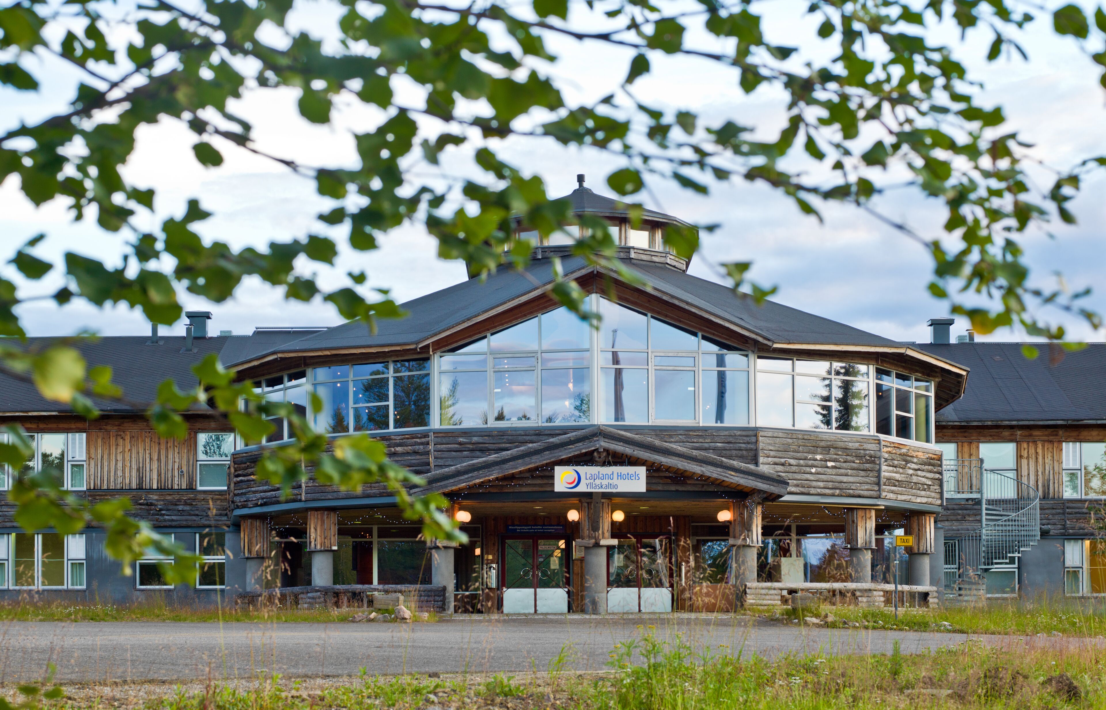 Un hotel modern amb una gran façana de vidre, elements exteriors de fusta i un rètol de Lapland Hotels.