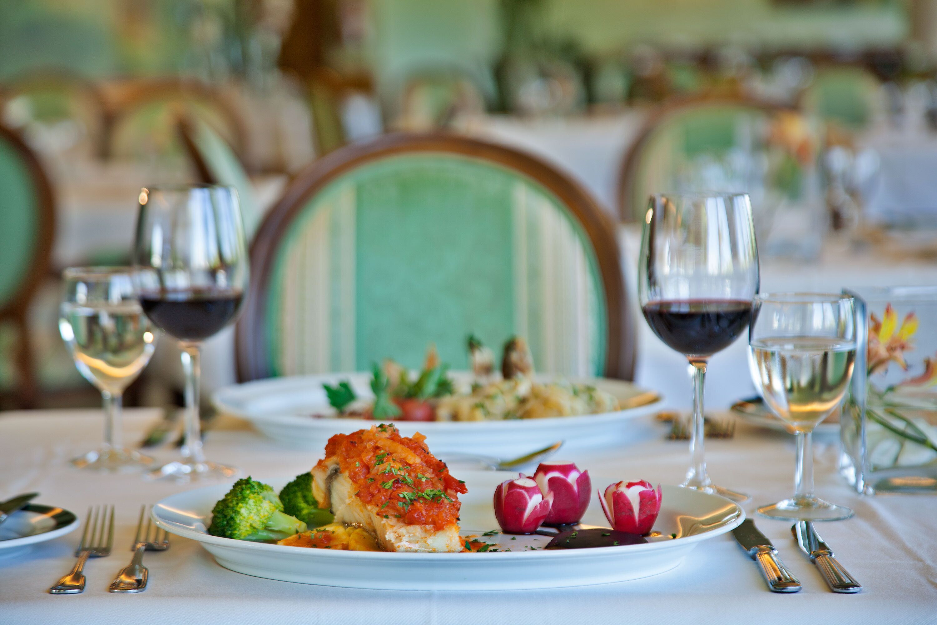 A dining table set with plates of food, wine glasses, and cutlery.