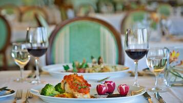 A dining table set with plates of food, wine glasses, and cutlery.