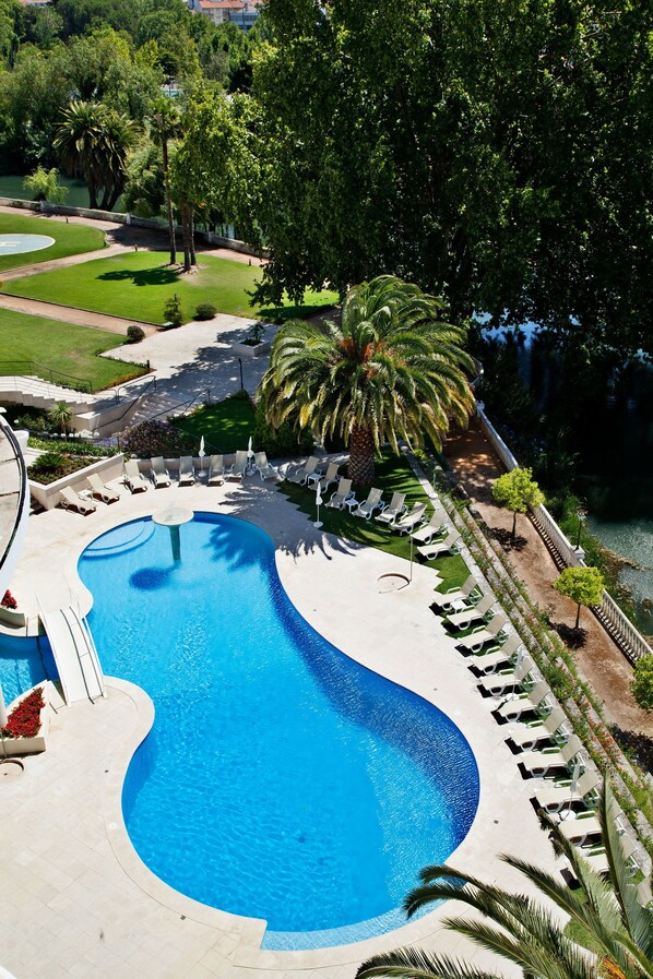 Una piscina con sillones de descanso y palmeras.