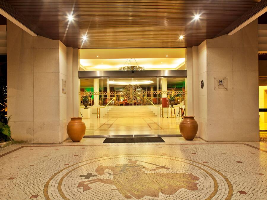 Entrada de hotel con piso de baldosas, un gran mosaico circular y dos jarrones grandes.