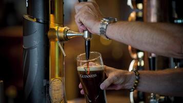 A person pouring Guinness beer from a tap into a glass.