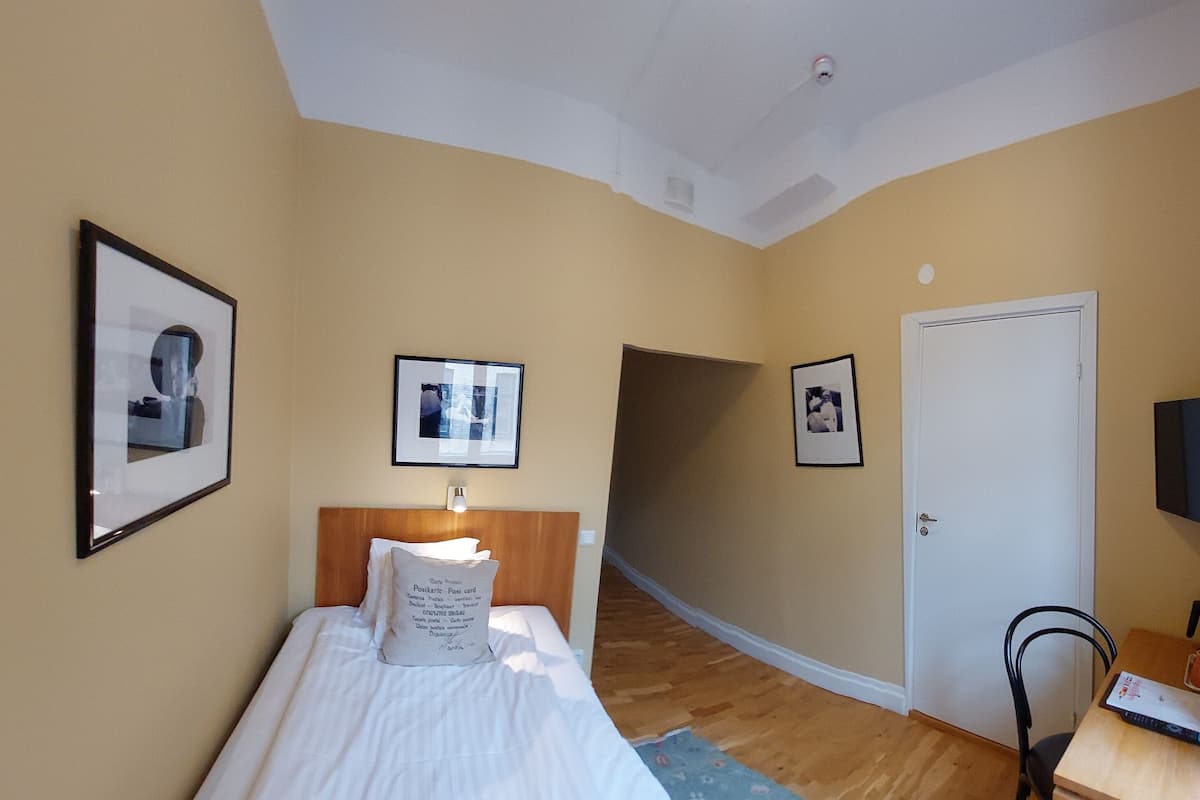 Habitación de hotel con cama, escritorio, silla, televisor y cuadros en las paredes.