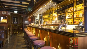 A bar area with stools, a bar counter, and shelves of bottles. - Hotel Bishops Arms Lund (Lund)