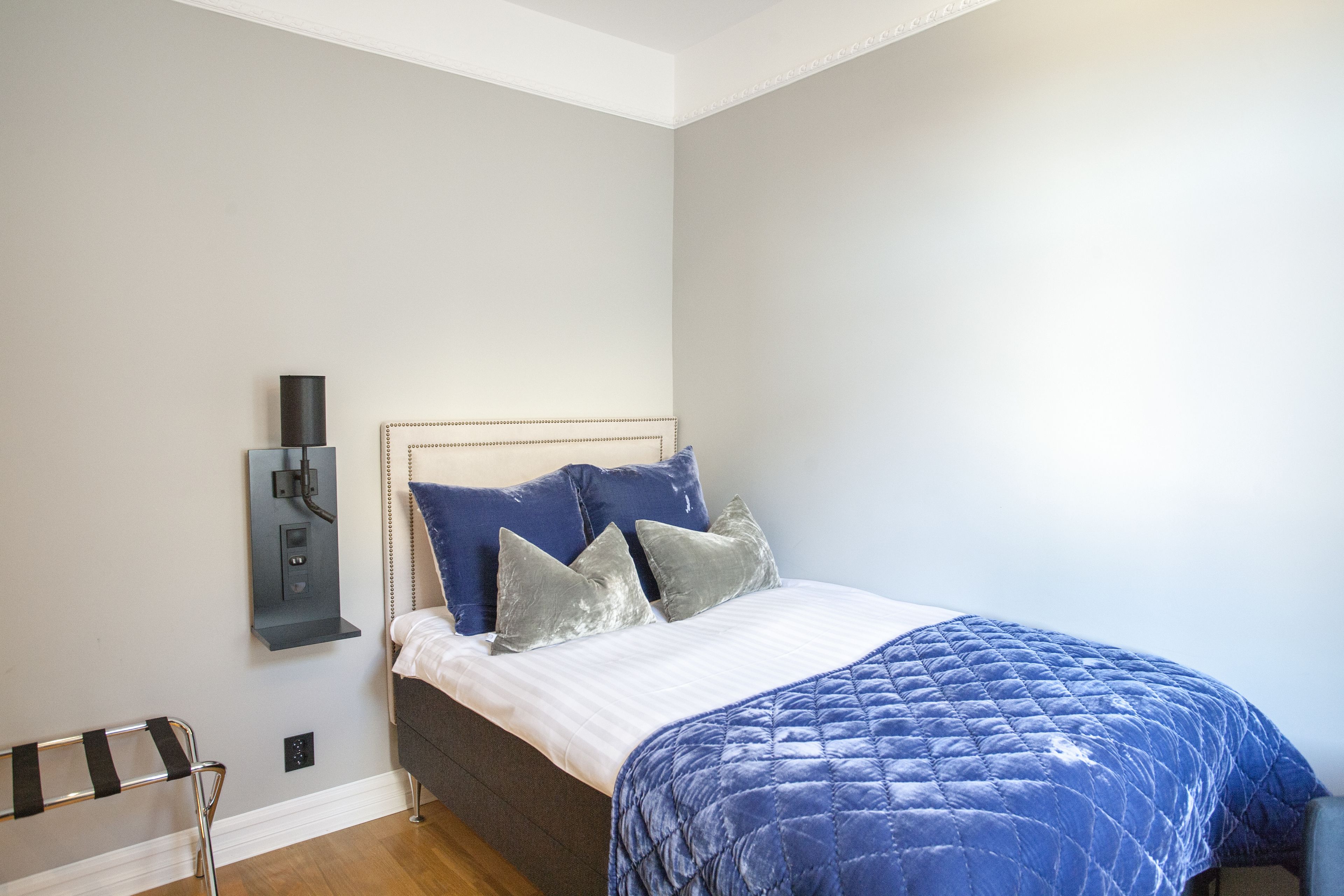 A bedroom with a bed, a bedside table, a lamp, and a chair.