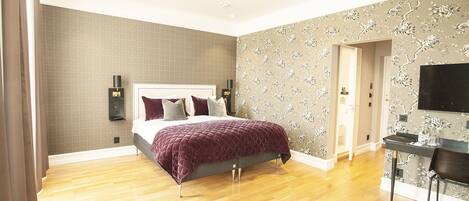 A modern bedroom with a large bed, a desk, and a chair.