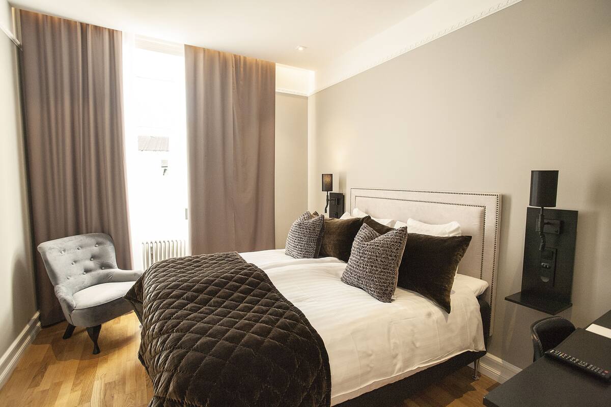 A hotel room with a bed, a chair, a desk, and a television.