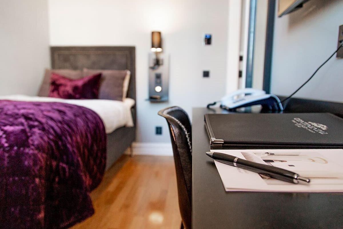 A bedroom with a bed, a desk with a laptop, and a chair.