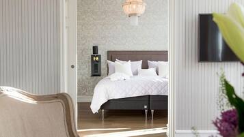 Een slaapkamer met een bed, een nachtkastje, een tv aan de muur en een kroonluchter.