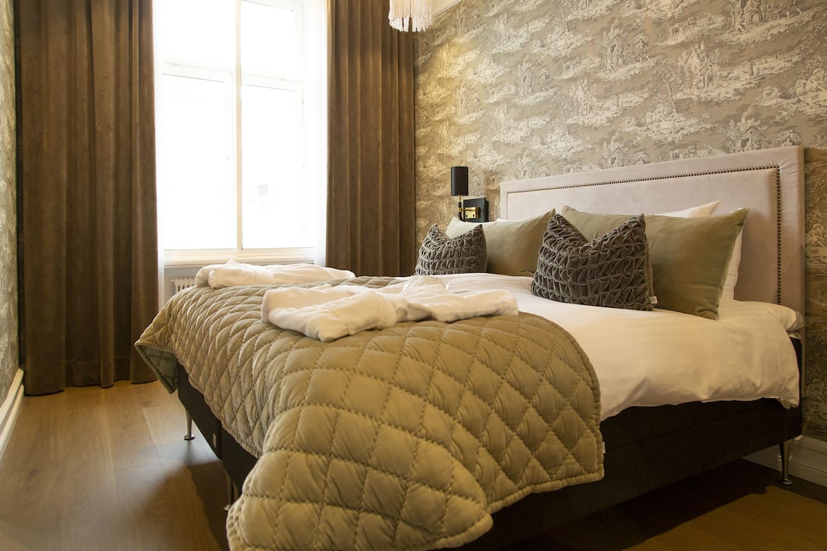 A neatly made bed with a quilted blanket, a headboard, and decorative pillows.