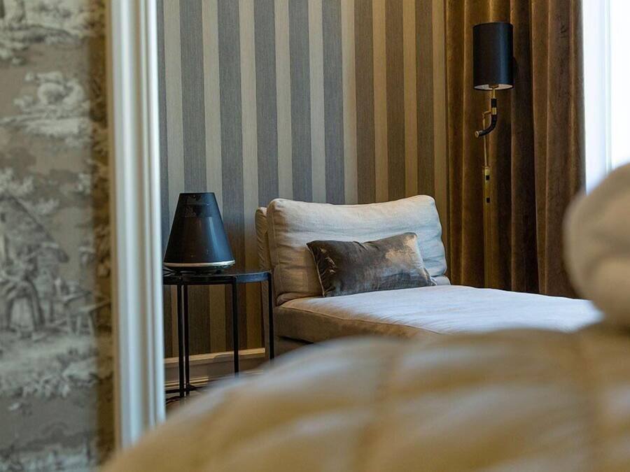 A bedroom with a bed, a nightstand, a lamp, and a striped wall.