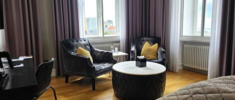 A hotel room with a bed, two armchairs, a small round table, and a radiator.